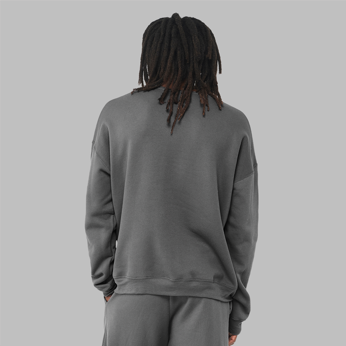 The back of a man wearing a charcoal grey crew sweatshirt to show the loose fit and that there is no logo.