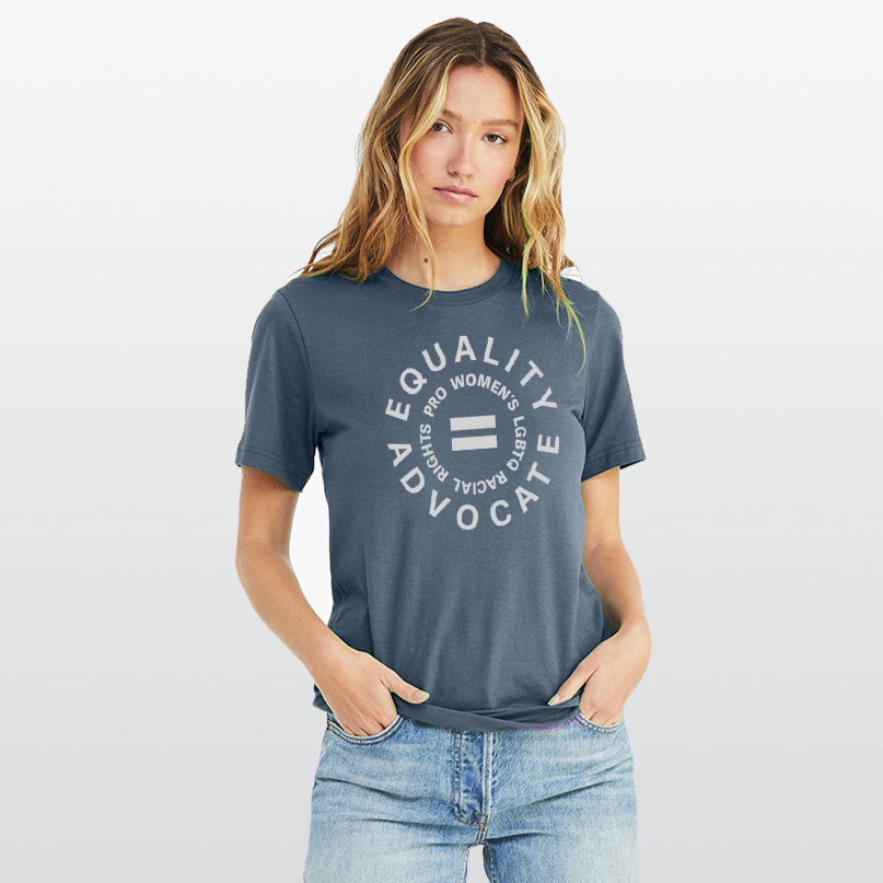 A lady wearing an equal rights, Slate Blue t-shirt, with a light grey logo. An equal sign is in the middle with the text Equality Advocate, pro women's, LGBTQ, & racial rights around it.