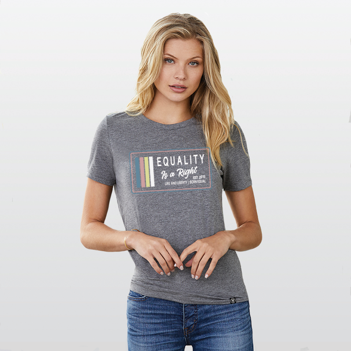 Lady wearing a grey t-shirt with the text, Equality, Life and Liberty, and Born Equal, in white bold font. The text, Is a Right, is in white script font. On the side of the logo are stripes of the colors Slate Blue, Dusty Rose, Bisque Gold, and white.