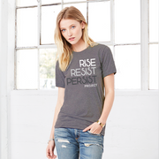 A lady wearing a political unisex Slate Purple t-shirt. The text says Rise, Resist, Persist, Project. The font is white, Slate Blue, and grey.