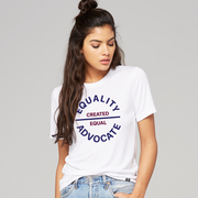 Lady wearing a white equality crew tshirt with a large circular center chest logo. The text Equality Advocate is in navy blue bold font, and the text Created Equal is in maroon bold font.