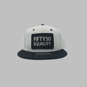 A black flat bill equality hat with a black bill and eyelets. It has a sewn on black patch that has the embroidered text Fifty50, Equality, in bold, grey font.