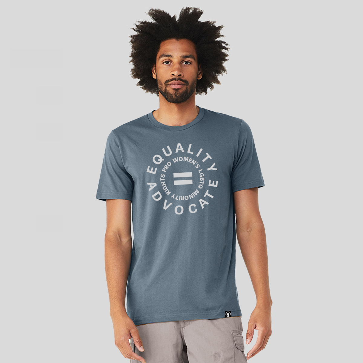 Man wearing a Slate Blue human rights tshirt with a light grey logo. An equal sign is in the middle with the text Equality Advocate, and pro women's, lgbtq, and minority rights in a circle around it. 