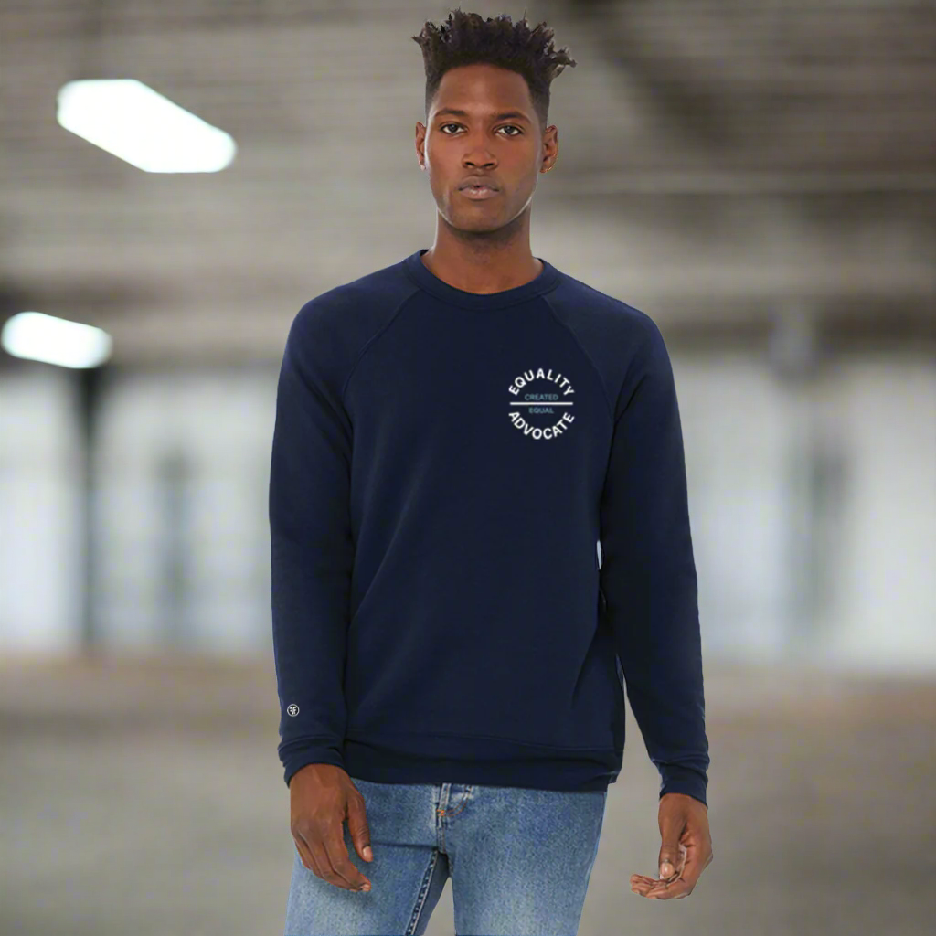 A man wearing a navy blue equality crew sweatshirt with a left chest circular logo. The text Equality Advocate is in white, bold font, and the text Created Equal is in Slate Blue, bold font.