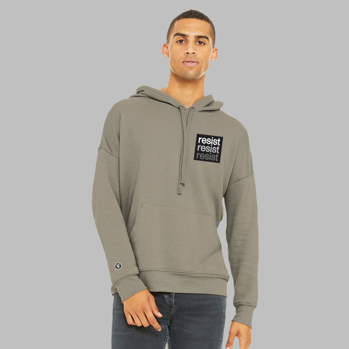 A man wearing a stone taupe, unisex political hoodie. The logo is a left chest black square, with text that says Resist, three times in white, light grey and dark grey.  