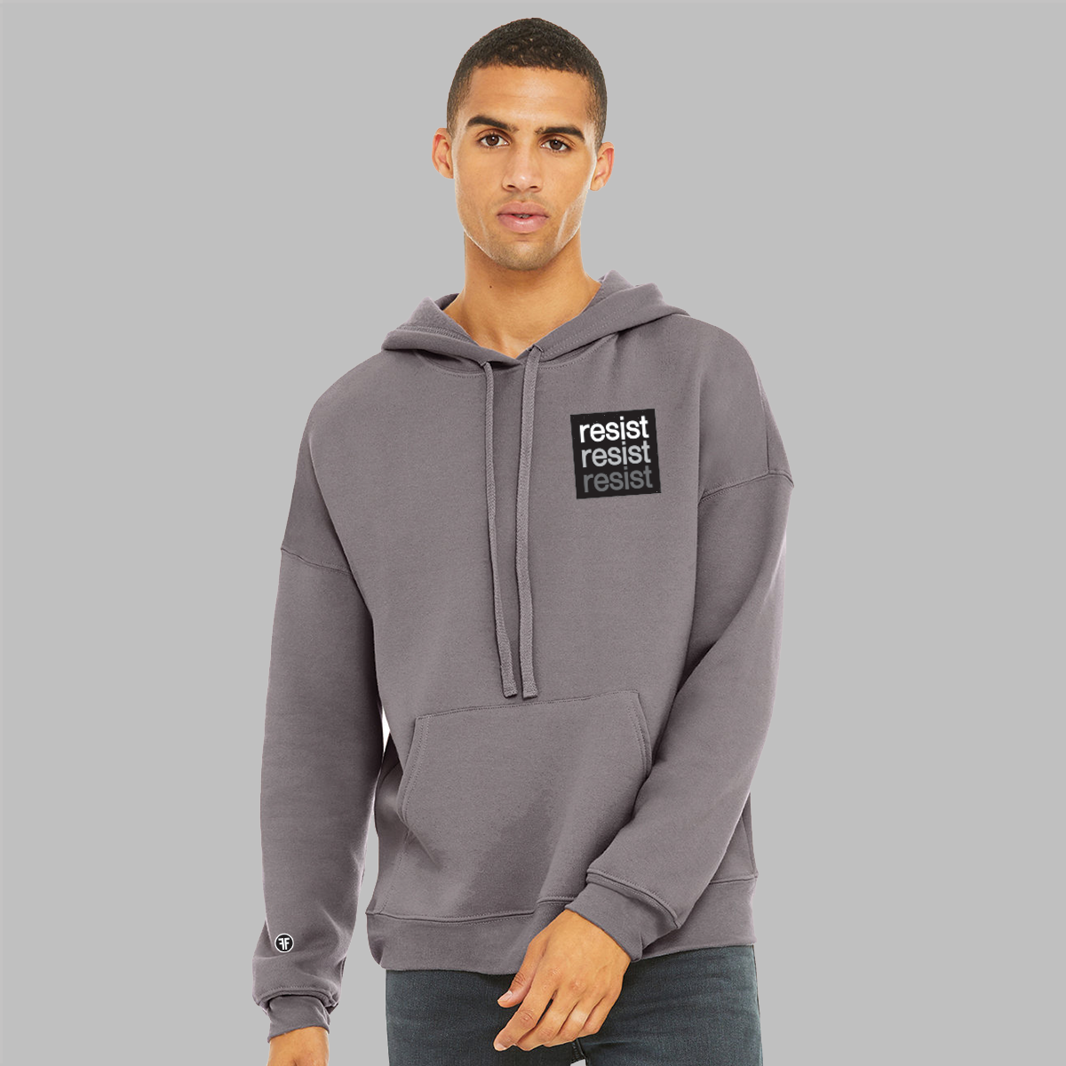 A man wearing a slate purple, unisex political hoodie. The logo is a left chest black square, with text that says Resist, three times in white, light grey and dark grey.  