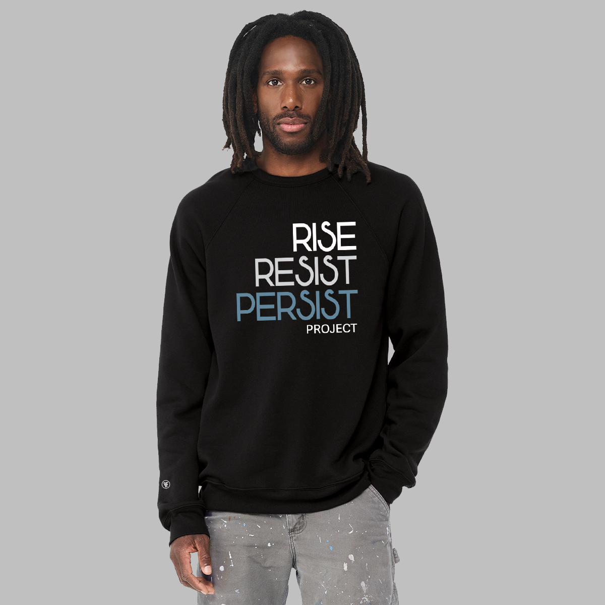 A man wearing a political unisex black sweatshirt. The text says Rise, Resist, Persist, Project. The font is white, Slate Blue, and grey.