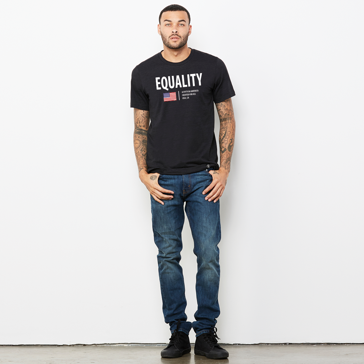 A man wearing a black t-shirt. The logo has the text, Equality, written in white bold font, and an American flag and the text, A fifty 50 America created for all.